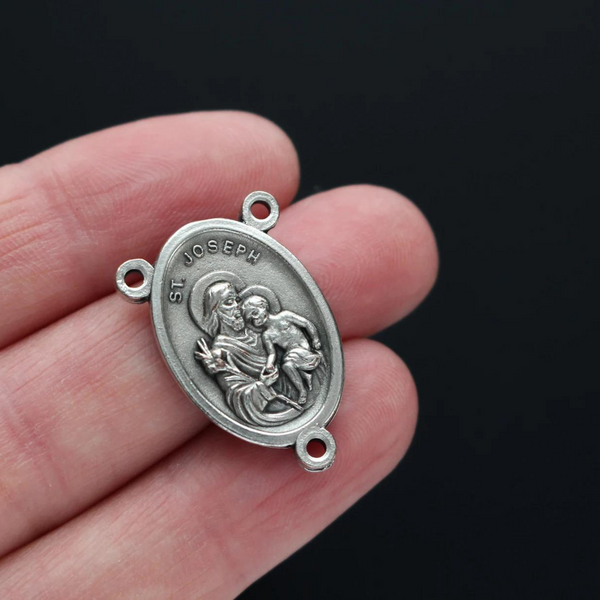 Saint Joseph rosary centerpiece. The front of the medal depicts Saint Joseph holding child Jesus in one arm and a lily in the other. The reverse side is marked "Pray For Us"