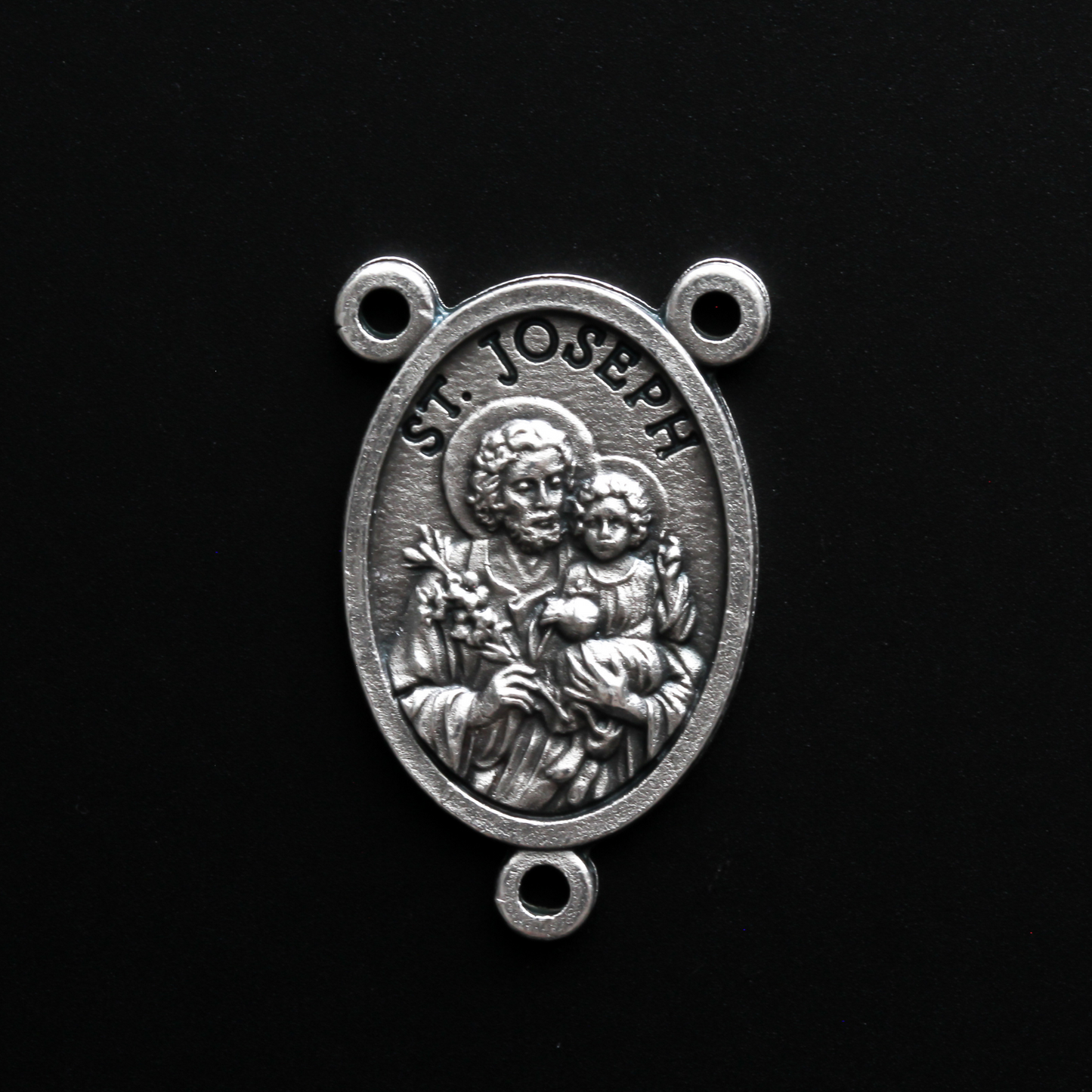 Saint Joseph rosary centerpiece that depicts Joseph holding child Jesus in one arm and a lily in the other