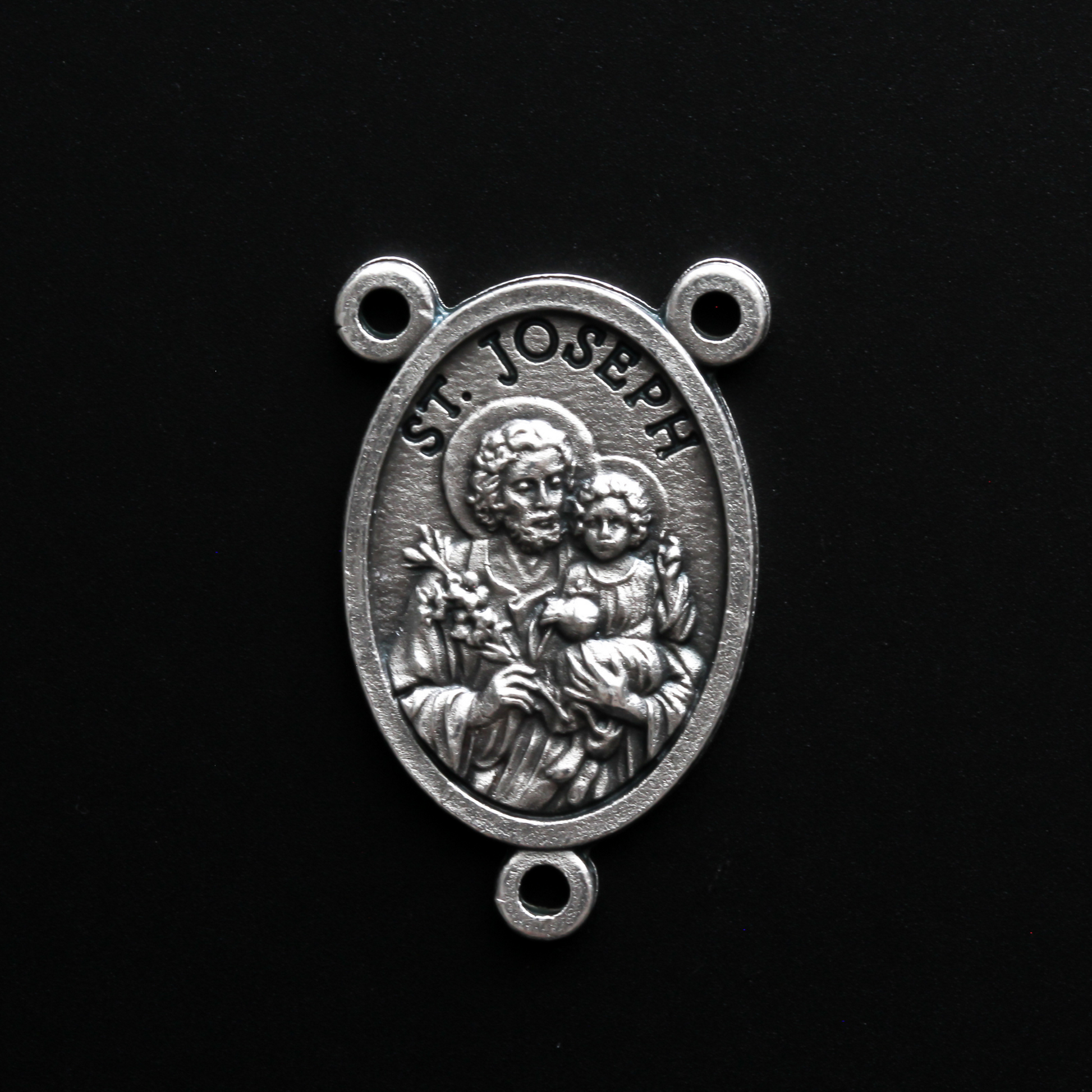 Saint Joseph rosary centerpiece that depicts Joseph holding child Jesus in one arm and a lily in the other