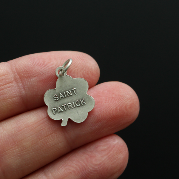 Small silver-tone St. Patrick shamrock-shaped charm. The front depicts Saint Patrick and the reverse is marked "Saint Patrick"