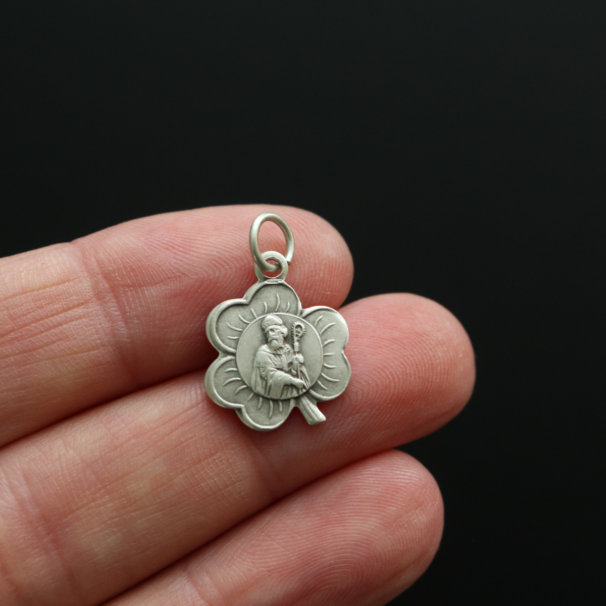 Small silver-tone St. Patrick shamrock-shaped charm. The front depicts Saint Patrick and the reverse is marked "Saint Patrick"