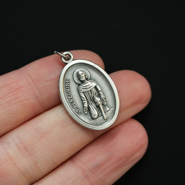Saint Peregrine medal that depicts the saint on the front and is marked "Pray For Us" on the back