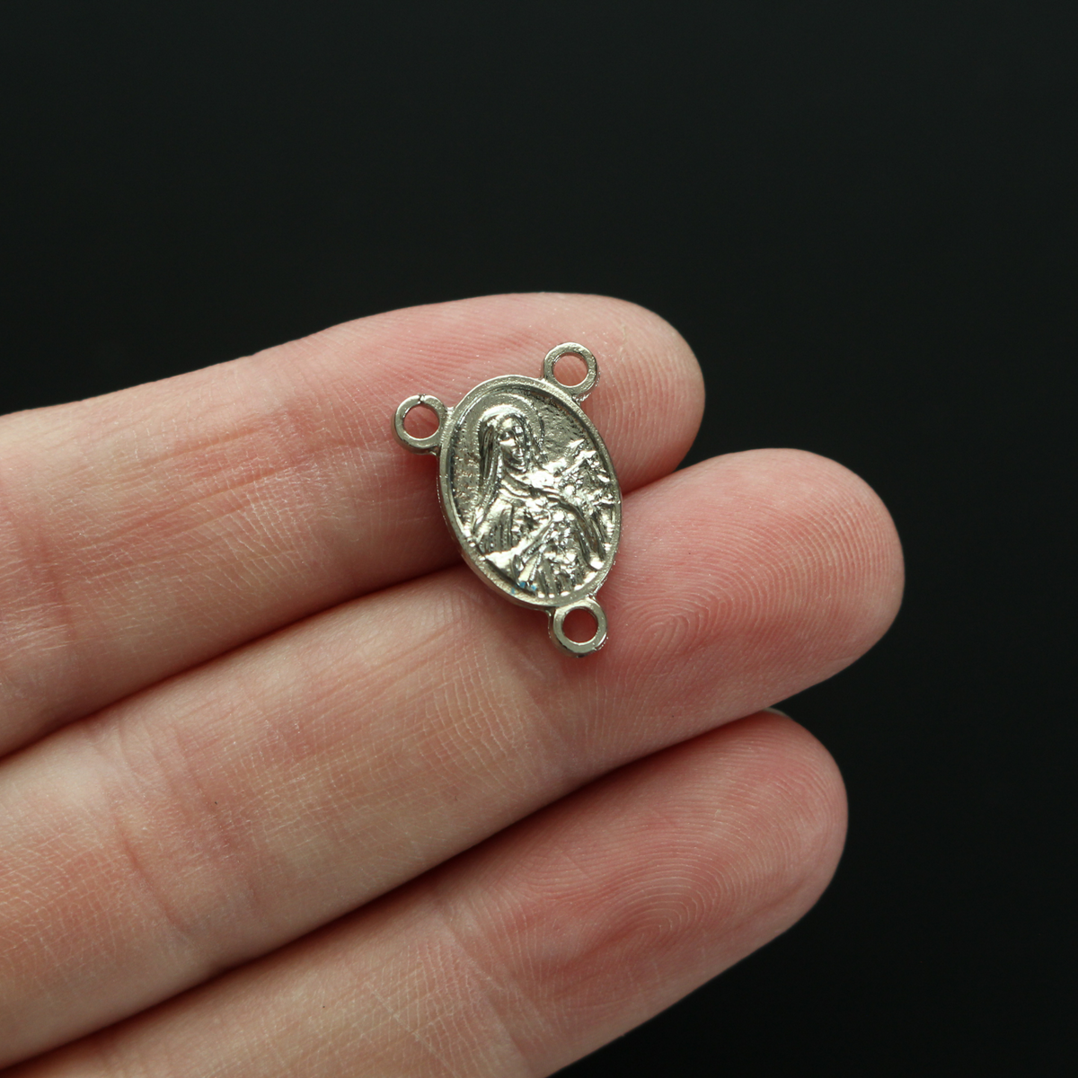 Silver-tone Saint Therese of Lisieux rosary centerpiece. There is a third-class relic from the soil beneath her coffin on the backside of the centerpiece.