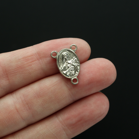 Silver-tone Saint Therese of Lisieux rosary centerpiece. There is a third-class relic from the soil beneath her coffin on the backside of the centerpiece.