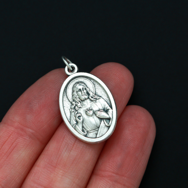 One inch oval medal that features an image of The Immaculate Heart of Mary on the front with an image of The Sacred Heart of Jesus on the back